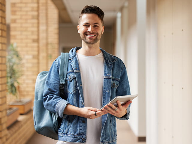 Homem na faculdade com mochila nas costas e sorrindo