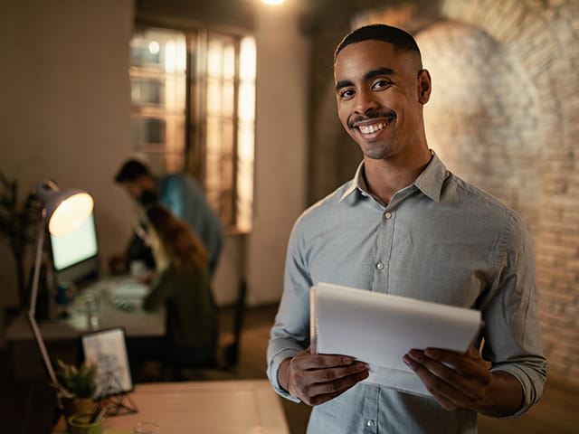 Homem sorrindo enquanto segura um caderno